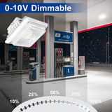 A square white LED outdoor light fixture shown floating over a gas station scene, with text reading '0-10V Dimmable' and a dimming percentage dial at the bottom. The product is the light fixture, not the gas station environment.