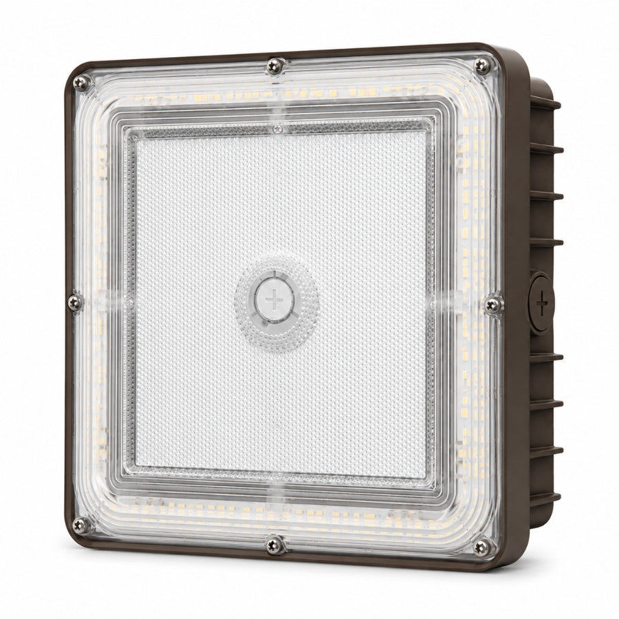 A square industrial LED light fixture with a clear protective lens, showing the internal LED strip and a brown metal housing with side heat fins.