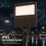 A bronze commercial LED parking lot light mounted to a pole, shining brightly while operating in a heavy downpour at night.