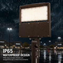 A bronze commercial LED parking lot light mounted to a pole, shining brightly while operating in a heavy downpour at night.